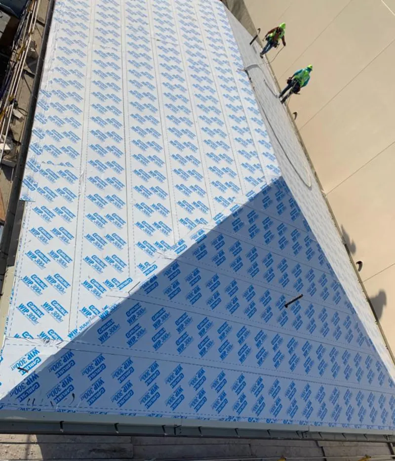 Professional roofers installing underlayment on a metal roof in Wolfeboro